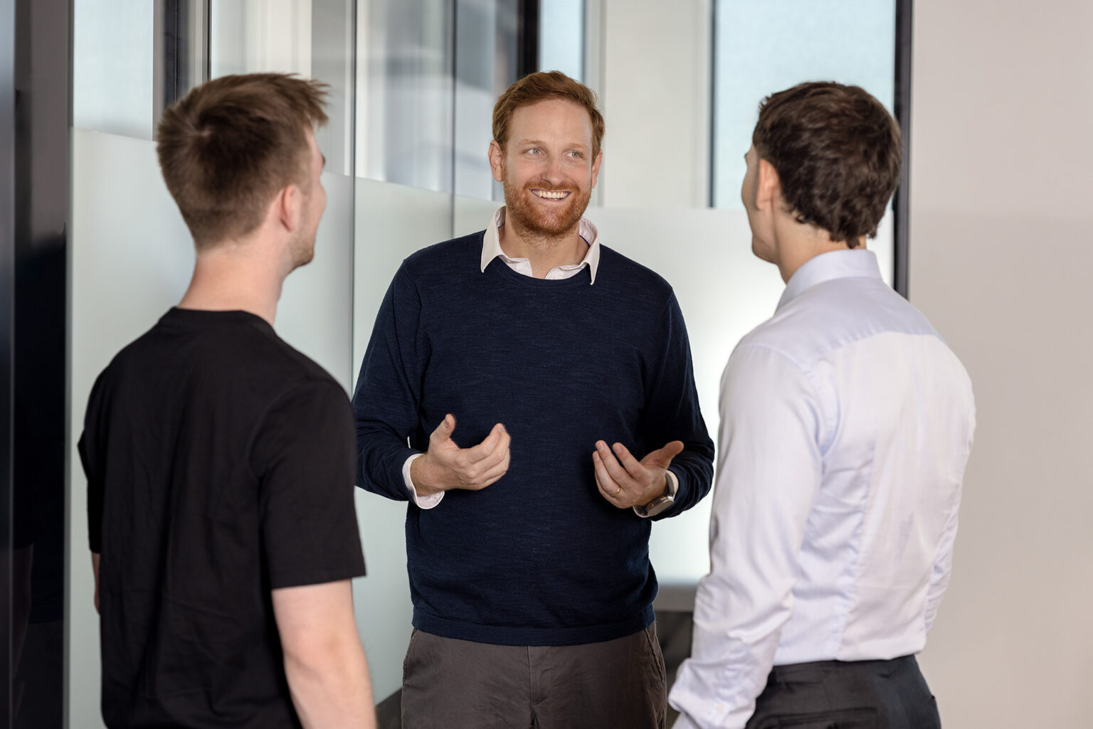 Teammitglieder des Investitionsbereichs „Venture Capital“: Drei Männer sind in einem lockeren Gespräch miteinander.